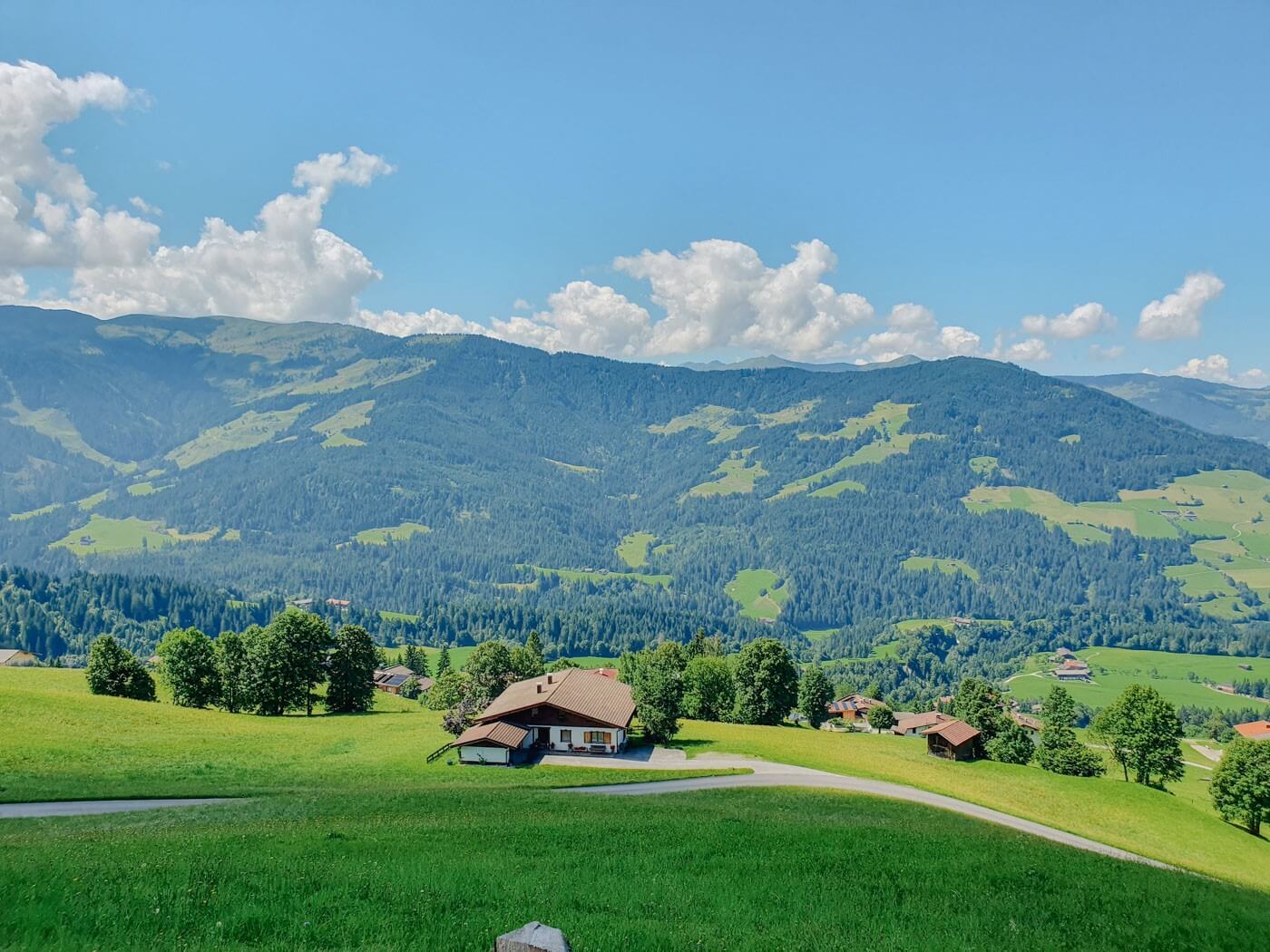 Bergpanorama, ein Bauernhof und Wiesen im Brixental