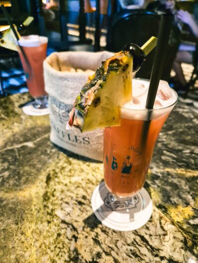 Zwei Singapur-Sling-Cocktails mit Erdnuss-Säckchen in der Mitte